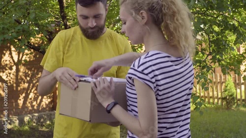 The postman delivers a parcel for a young woman photo