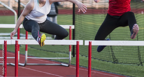 Two females running the hurdles in a race