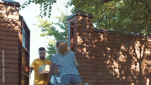 The postman delivers a parcel for a young woman photo