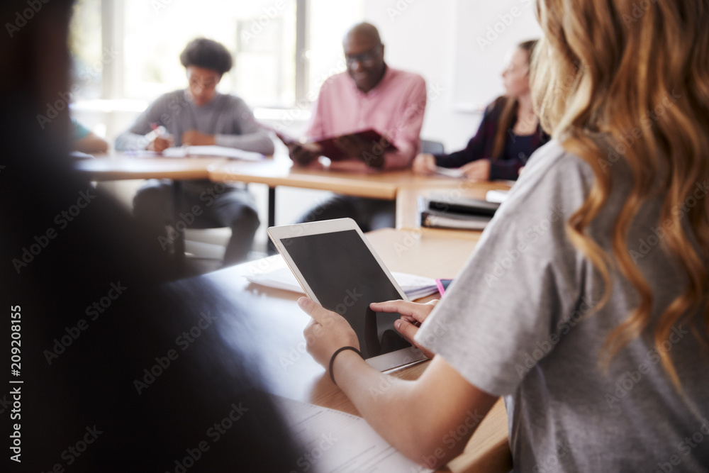 Female High School Student Using Digital Tablet Whilst Sitting At Desk In Class Female High School Student Using Digital Tablet Whilst Sitting At Desk In Class