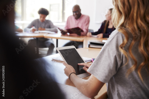 Female High School Student Using Digital Tablet Whilst Sitting At Desk In Class