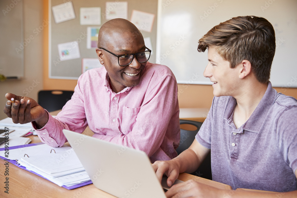 High School Tutor Giving Male Student One To One Tuition At Desk High School Tutor Giving Male Student One To One Tuition At Desk