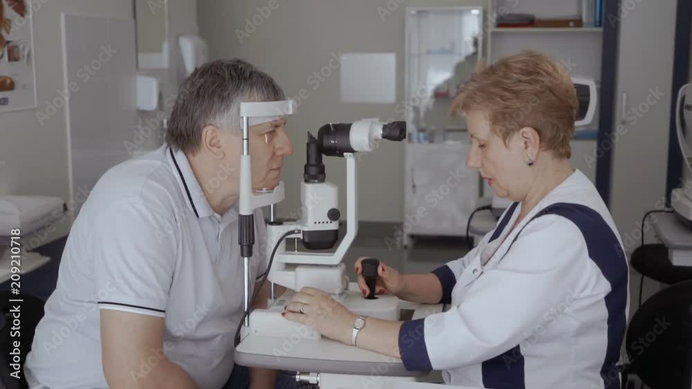 Doctor examining eyesight of adult man with modern equipment Doctor examining eyesight of adult man with modern equipment