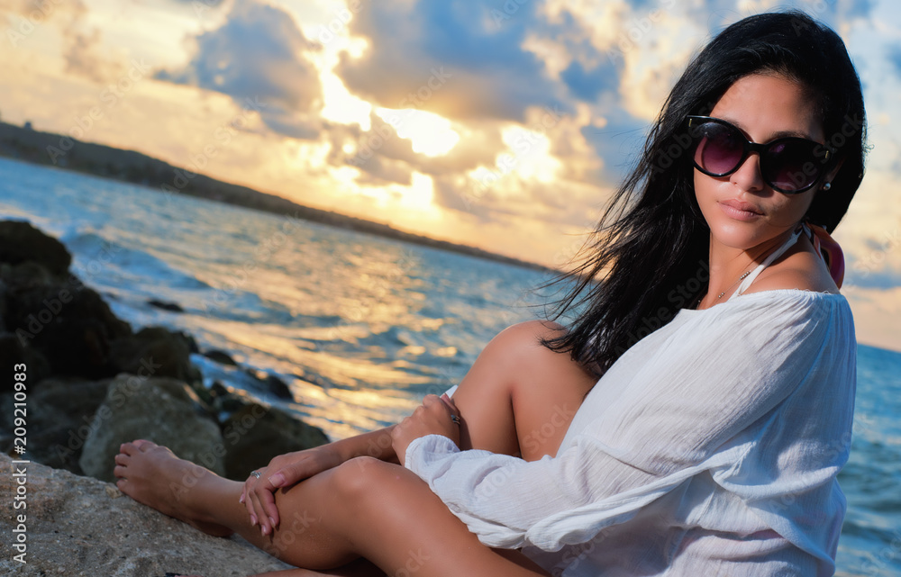 beautiful girl with sunglasses in the beach at sunset