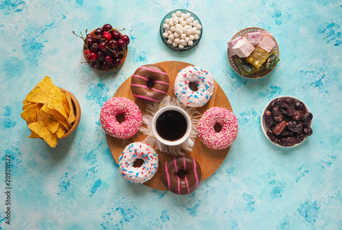 A cup of coffee and Donut sweets on a blue table.