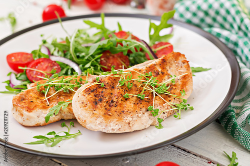 Grilled chicken fillet and fresh vegetable salad of tomatoes,red onion and arugula. Chicken meat salad. Healthy food.
