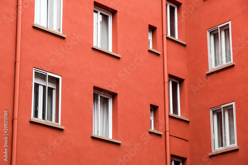Decorative white window on an old red urban wall .