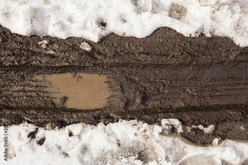 Tire Tracks in Mud from a dirt road with snow and ice.
