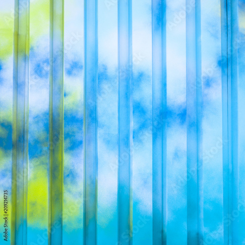 Colorfully painted wall of corrugated steal for background with blues and greens.