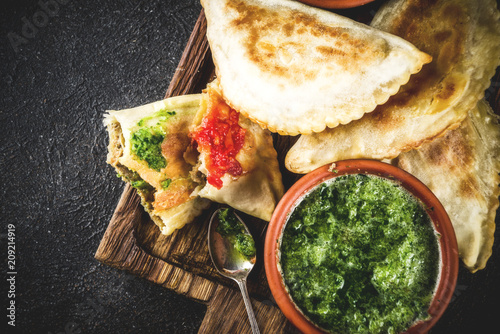 Latin American, mexican, chilean food. Traditional baked pastry empanadas with beef meat, two spicy sauces, dark rusty background copy space