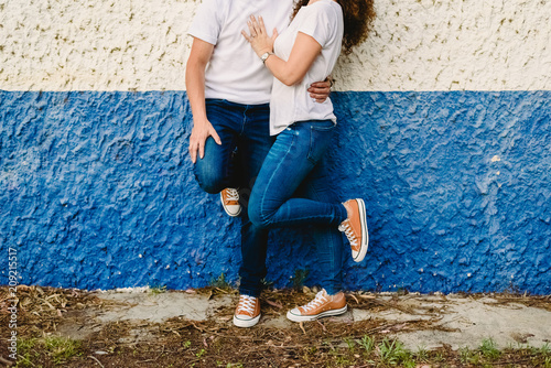 Couple of lovers resting on a blue and white wall in jeans