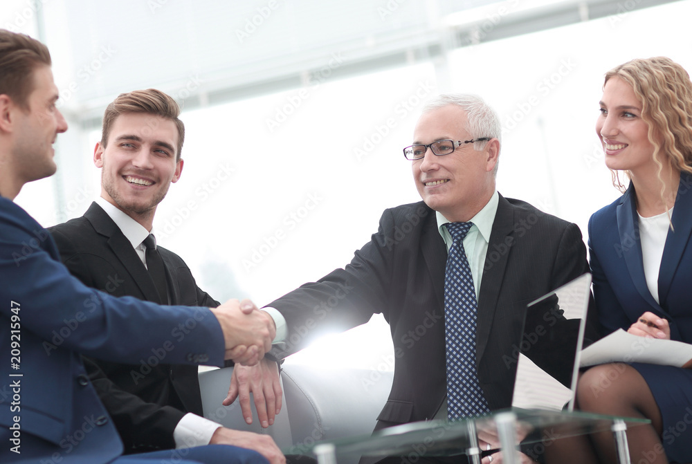 Partners concluding deal and shaking hands in the presence of team members Partners concluding deal and shaking hands in the presence of team members