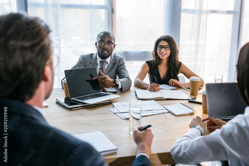 selective focus of group of multiethnic business colleagues discussing strategy during business meeting in office