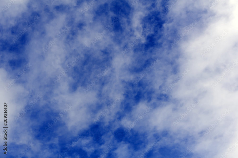 Obraz premium background - blue sky with tattered white clouds photographed from a close distance..