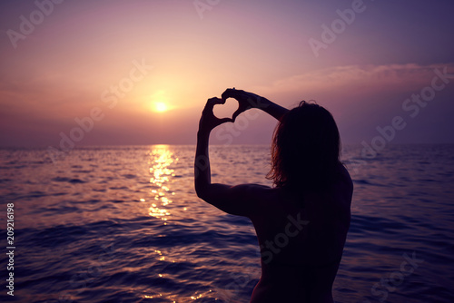 Heart shape made with hands  morning sun in the horizon. Heart against beautiful sunset.