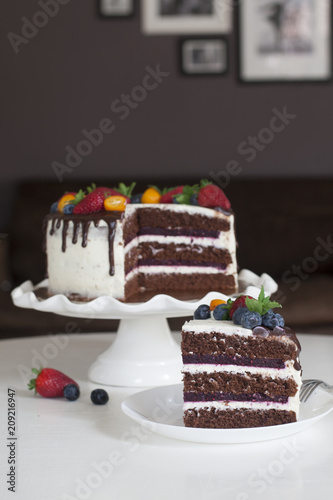 Festive chocolate cake with berry jelly, creamcheese and chocolate stains in home interior.