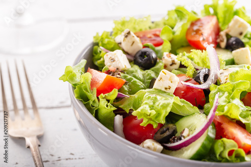 Fresh greek salad served in bowl with fork.