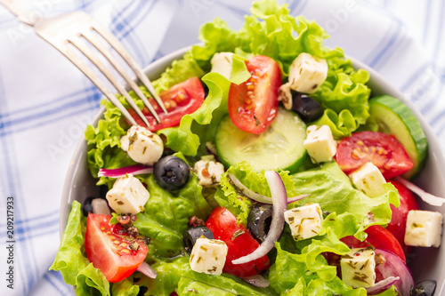 Fresh greek salad served in bowl with fork.