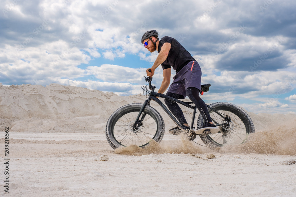 Training a bicyclist in a chalky quarry. A brutal man on a fat bike.	
