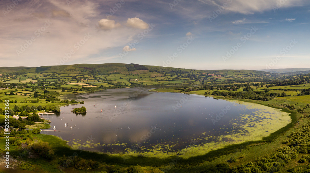 Aerial panoramic view of a beautiful natural lake surrounded by rural farmland (Llangorse Lake, Wales)