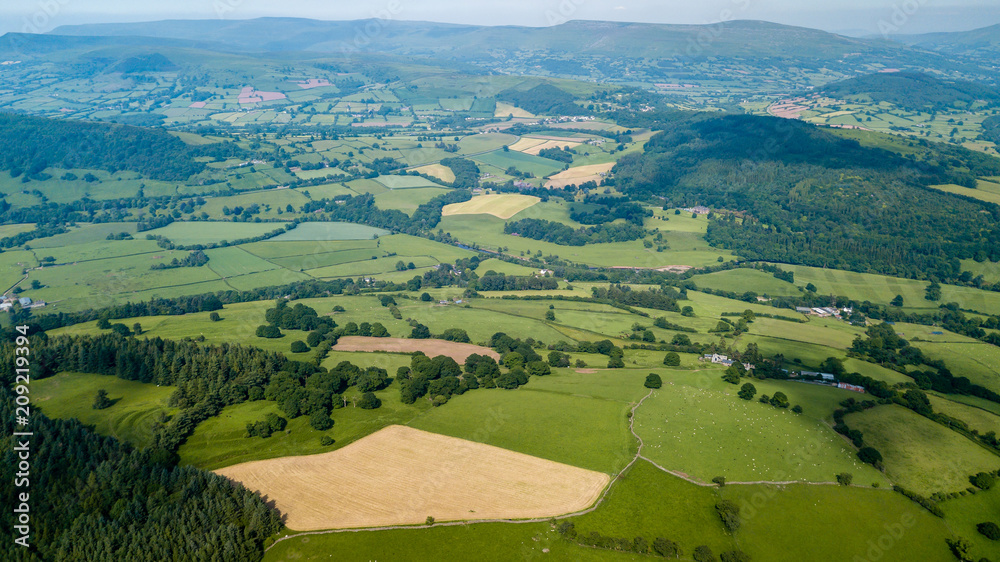 Aerial drone view of rural Wales showing farmed fields and green rolling hills