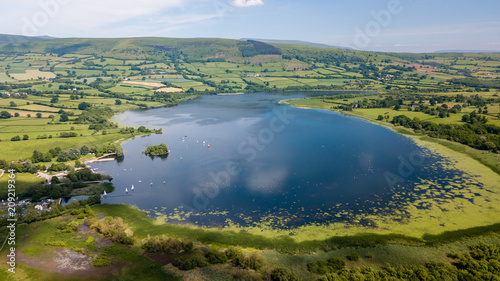 Aerial drone view of a beautiful lake surrounded by rural farmland (Llangorse Lake, Wales) photo