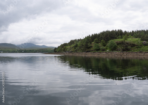 Beautiful beach  with mountains in the background and cloudy skies  with forest along the coast. Taken in Letterfrack along the Wild Atlantic Way  Ireland in summer.