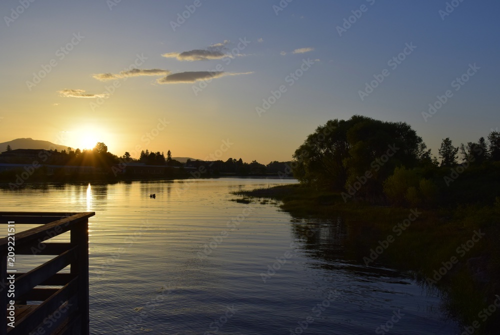 Obraz premium View across a pond lined with silhouettes of trees during sunset, Courtenay BC