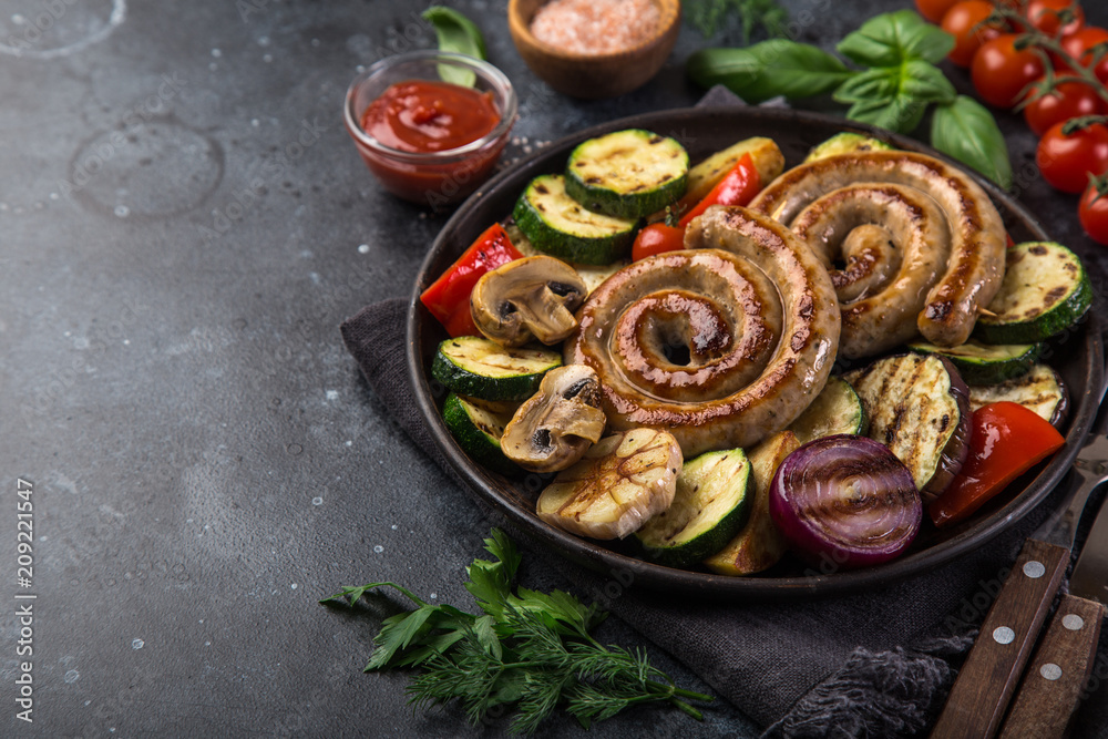 grilled spiral sausages and vegetables on dark plate