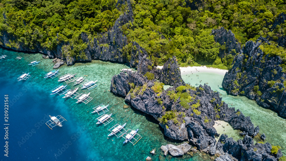 Aerial drone view of tourist boats over a tropical coral reef and small sandy because in the Bacuit Archipelago Aerial drone view of tourist boats over a tropical coral reef and small sandy because in the Bacuit Archipelago