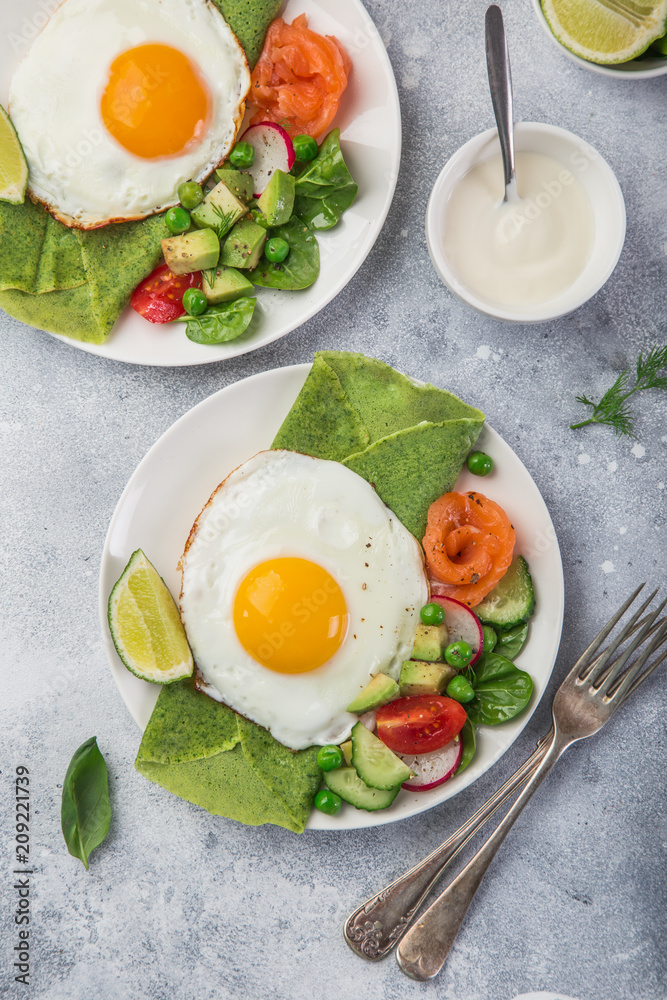 green spinach crepes with fried eggs, smoked salmon and vegetables for breakfast green spinach crepes with fried eggs, smoked salmon and vegetables for breakfast