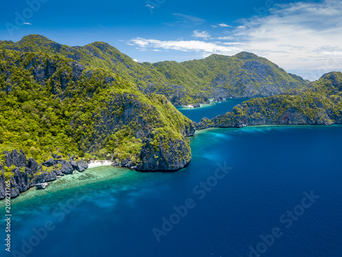 Aerial drone view of spectacular limestone cliffs, jungle, sandy beaches surrounded by coral reef