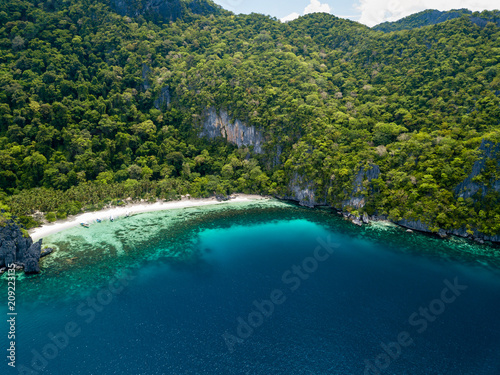 Aerial drone view of a spectacular tropical beach surrounded by dense jungle and jagged cliffs  Papaya Beach  Palawan 