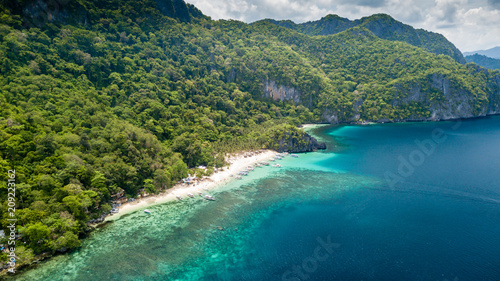 Aerial drone view of a spectacular tropical beach surrounded by dense jungle and jagged cliffs (Papaya Beach, Palawan) © whitcomberd
