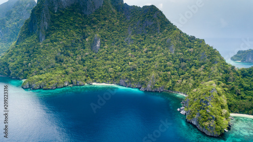 Aerial drone view of an unihabited tropical island with rugged mountains, jungle and sandy beaches
