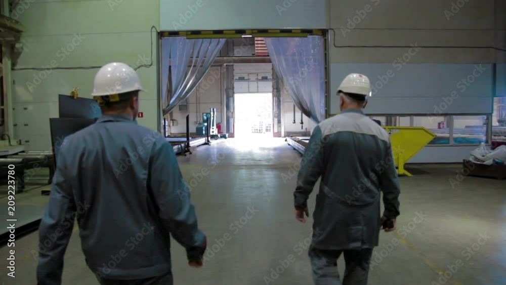 Two Engineer in Hard Hat is Walking Through Factory Two Engineer in Hard Hat is Walking Through Factory