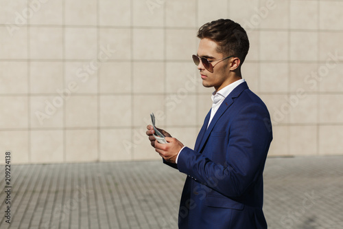 Photos Handsome young businessman walks with dollar cash along the street