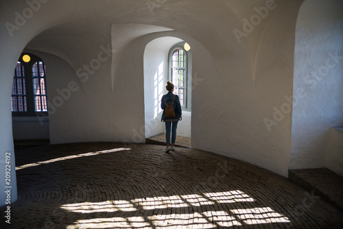 back view of young woman standing in beautiful historical building and looking at window, Interior of the Round Tower