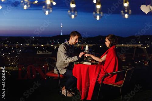 Lovely young man and woman have a romantic dinner on the rooftop in the night