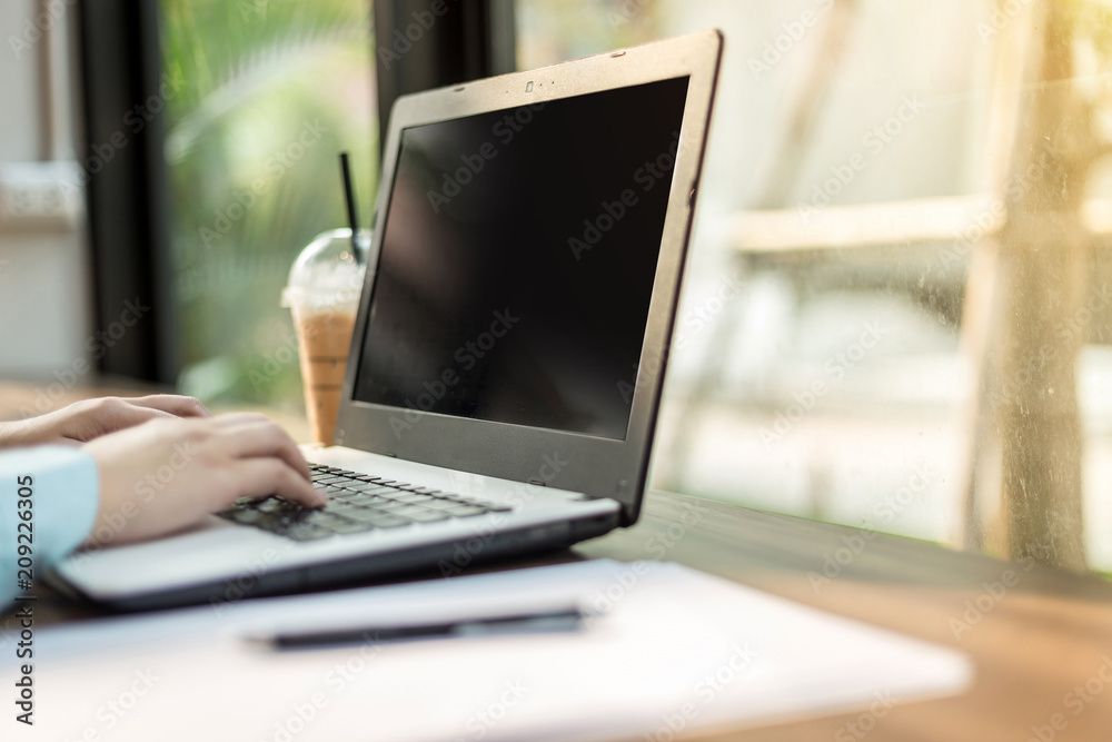 Fototapeta premium Close-up of business female working with laptop make a note document and smartphone in coffee shop like the background.