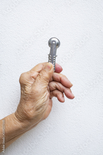 Senior woman's hand squeezing clothes peg on white background