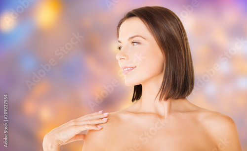 wellness and beauty concept - portrait of beautiful bare woman over holidays lights background