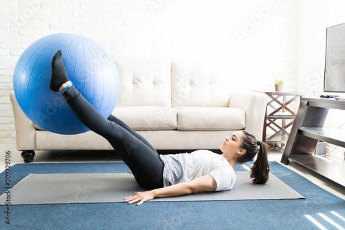 Fit woman lifting exercise ball with legs photo