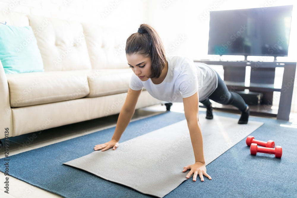 Latin woman doing push ups at home Latin woman doing push ups at home