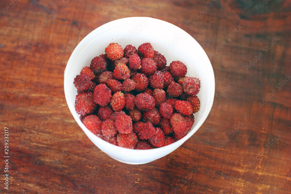 Raspberries in a cup on a wooden table