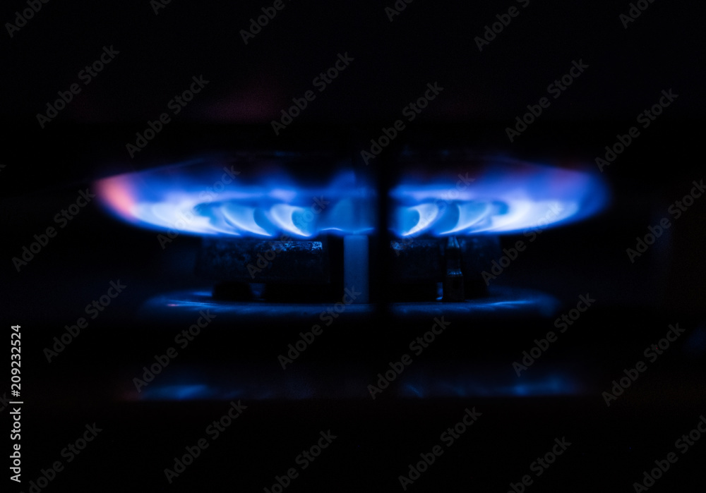 Close-up of blue fire burning from domestic kitchen stove in the dark
