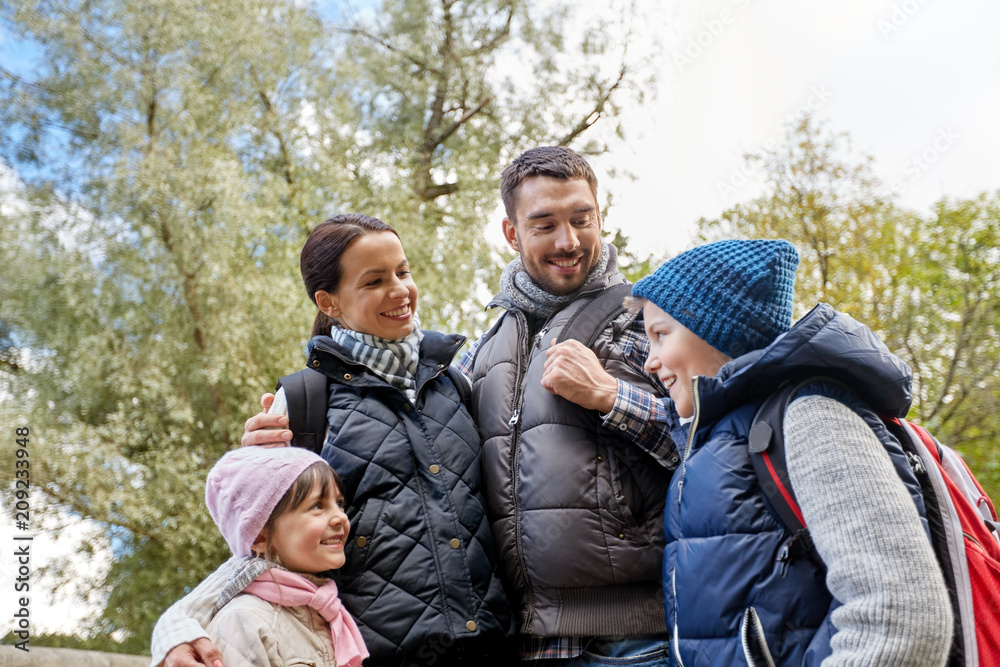 family, tourism and hiking concept - happy mother, father, son and daughter with backpacks in woods family, tourism and hiking concept - happy mother, father, son and daughter with backpacks in woods