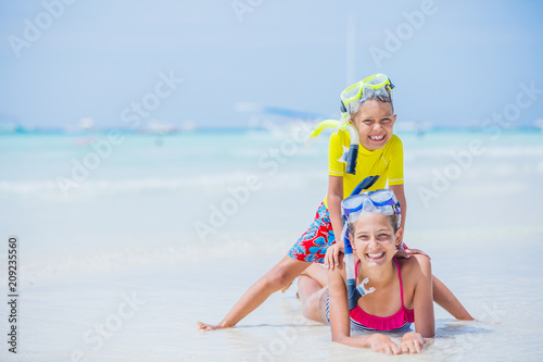 Brother and sister playing on the beach during the hot summer vacation day.