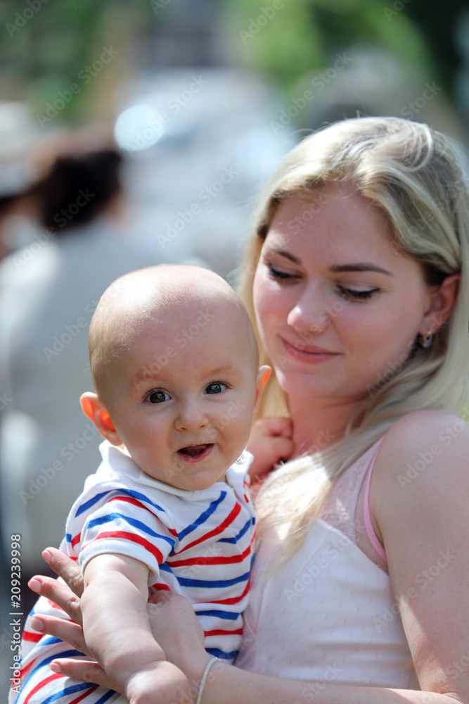 Beautiful Young Blonde Woman Holding A Cute Smiling Baby Boy In Her Arms Beautiful Young Blonde Woman Holding A Cute Smiling Baby Boy In Her Arms