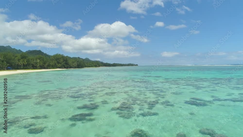 AERIAL: Flying over tranquil waters of the Pacific Ocean near spectacular tropical island. Cinematic shot of picturesque turquoise ocean and the spectacular tropical vegetation on remote island beach. AERIAL: Flying over tranquil waters of the Pacific Ocean near spectacular tropical island. Cinematic shot of picturesque turquoise ocean and the spectacular tropical vegetation on remote island beach.